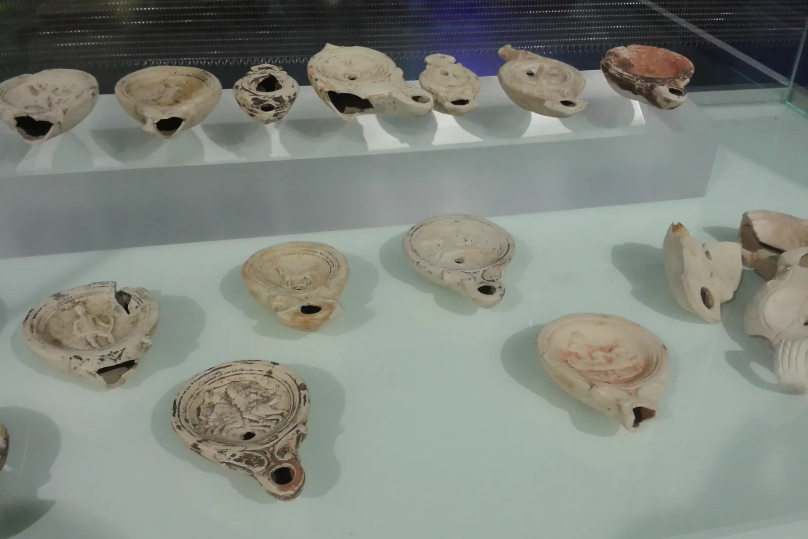 Rows of Roman clay oil lamps in a glass case at the Antiquarium beneath the Metropol Parasol